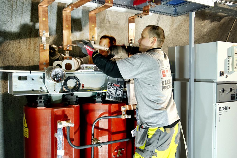 Arbetare monterar en hjuthartsisolerad transformator